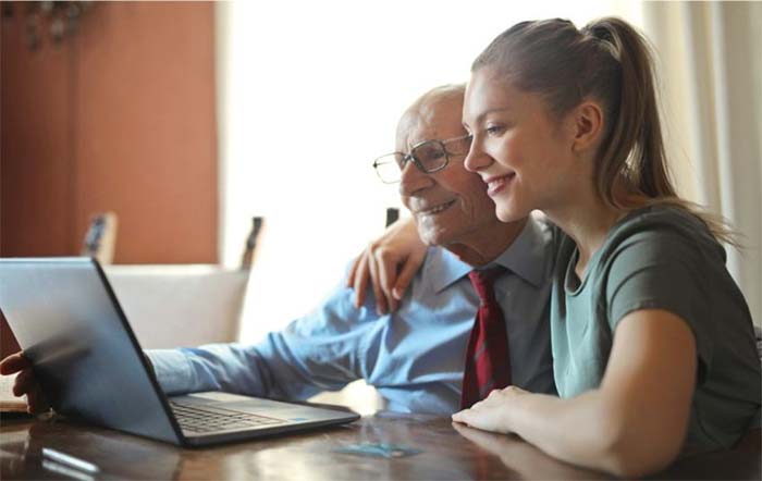 Happy grandfather and granddaughter looking at the laptop